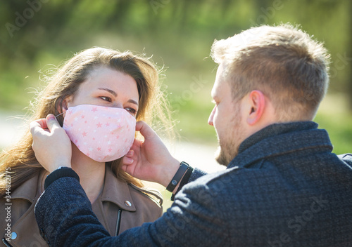 Masked young couple walking in the park photo