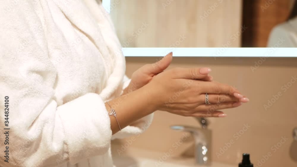 Woman puts on cream on her hands. Beauty and softness at home cream Woman puts on cream on her hands. Beauty and softness at home cream