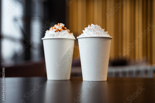 coffee in a paper cup with whipped cream on a table