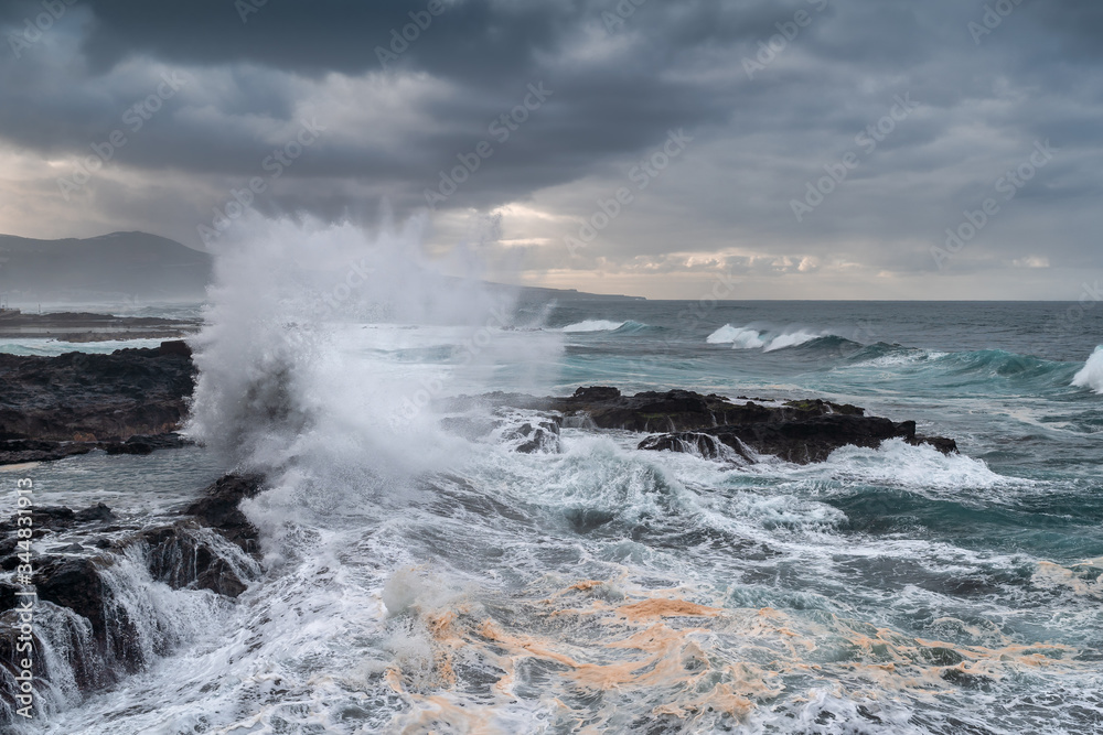 Paisaje marino  de la Playa del Puertillo con una gran ola rompiendo en las rocas. Arucas. Gran Canaria. Spain