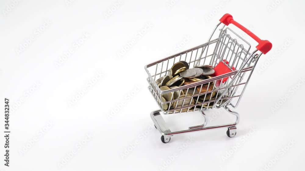 Hand pushing miniature toy supermarket trolley. There are a lot of metal coins in the cart. Collectibles, money saving and shopping concept.
