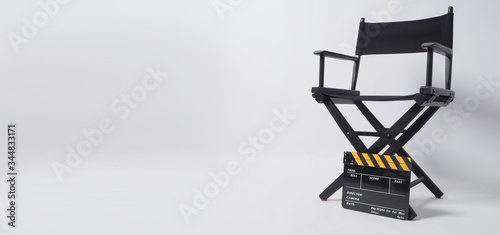 Clapper board or movie slate with director chair. It's black with yellow color on white background.
