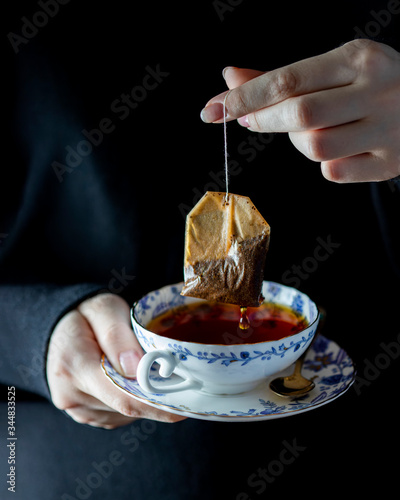 Close Up shot of female hands in a dark sweater holds a porcelain cup with burning tea.