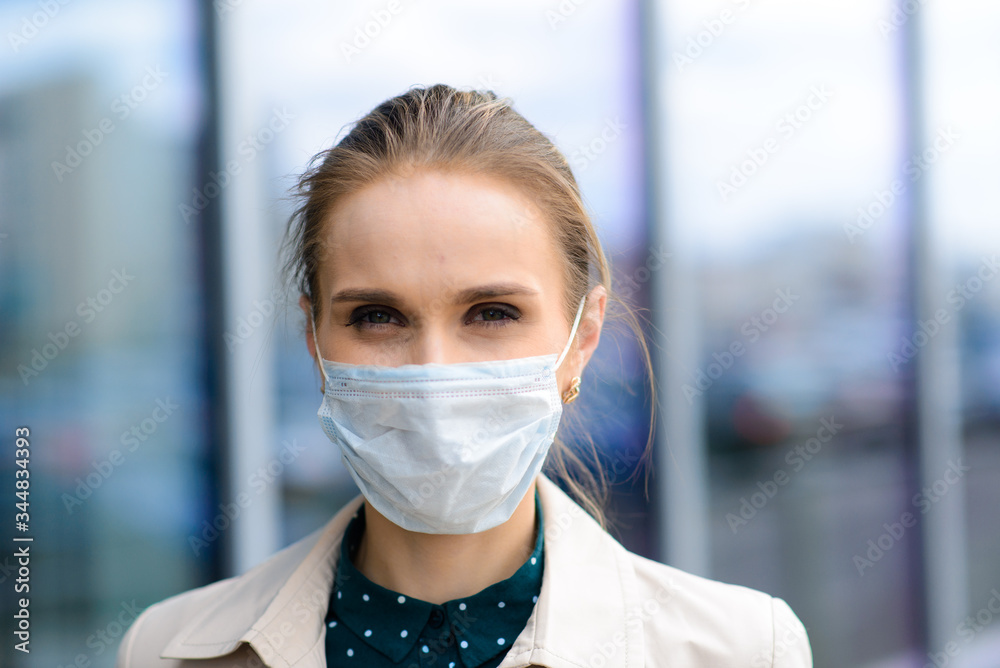 A young businesswoman wearing a health mask and talking on the phone in the city