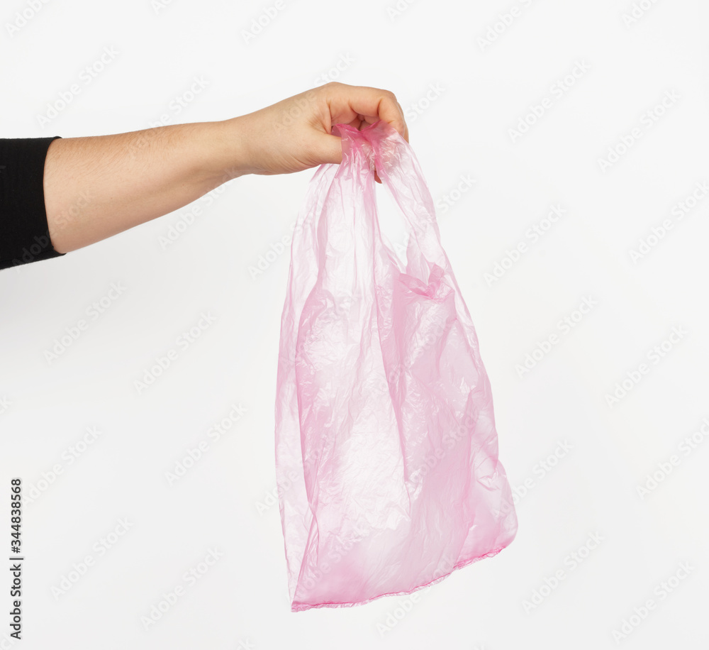 hand holds an empty pink plastic bag o hand holds an empty pink plastic bag o