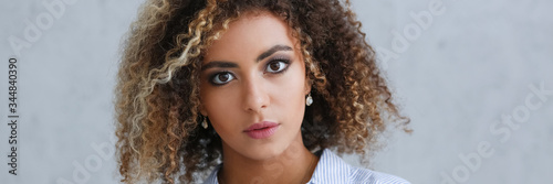 Beautiful black woman portrait. It's a gray background and does not smile beauty fashion style curly hair with white strands look the eye into the camera