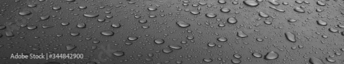 Drops of water on a black long metal surface, beautiful background after rain