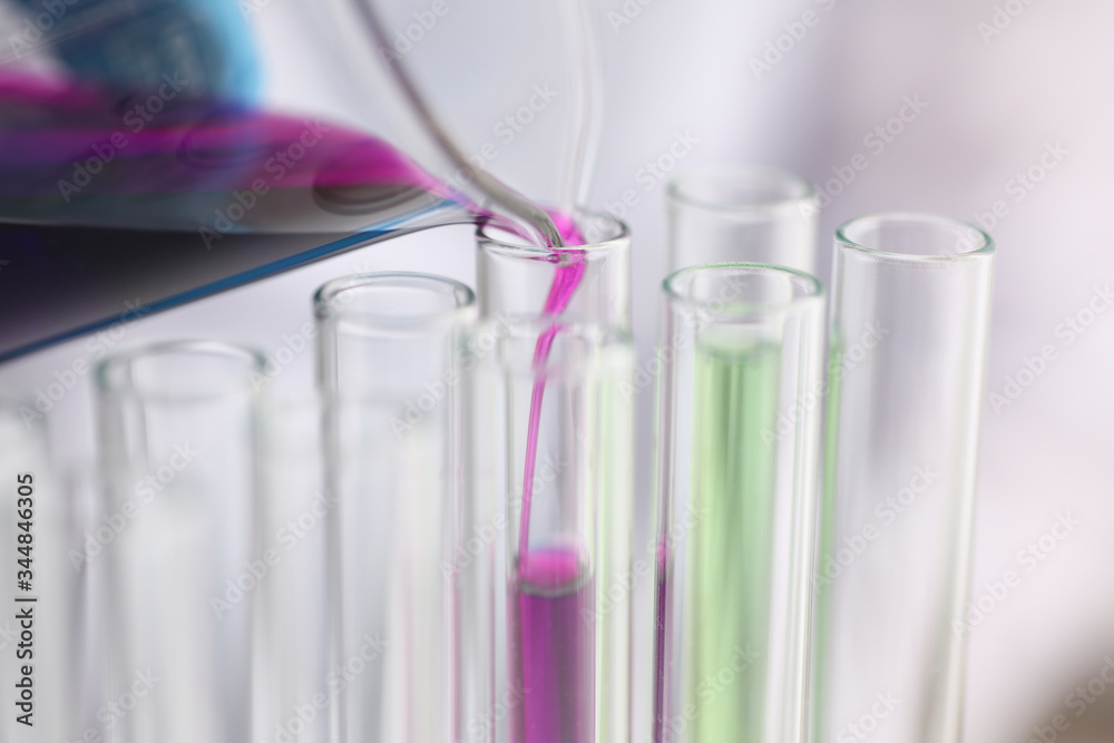 A male chemist holds test tube of glass in his hand overflows a liquid solution of potassium permanganate conducts an analysis reaction takes various versions of reagents using chemical manufacturing A male chemist holds test tube of glass in his hand overflows a liquid solution of potassium permanganate conducts an analysis reaction takes various versions of reagents using chemical manufacturing