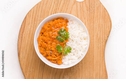 Dhal Indian lentil soup with rice and herbs in a white bowl on a wooden board