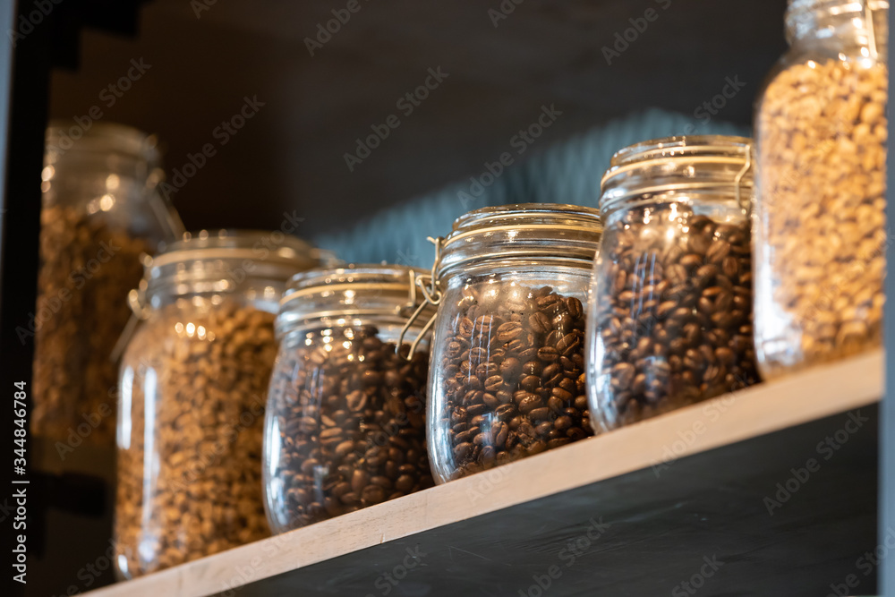 different roast coffee in glass jars on wooden shelf. different roast coffee in glass jars on wooden shelf.