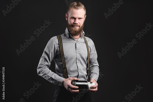 Handsome young man presents car parts on a gray background. The concept of sales and testing of goods