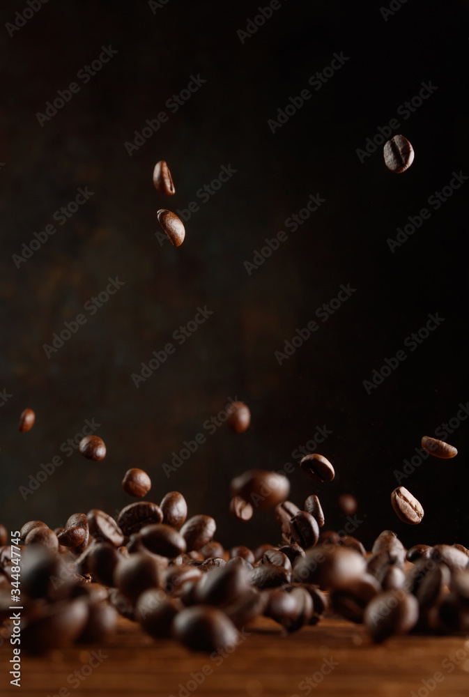 Obraz premium Many roasted coffee beans flying in the air over a wooden table. Selective focus