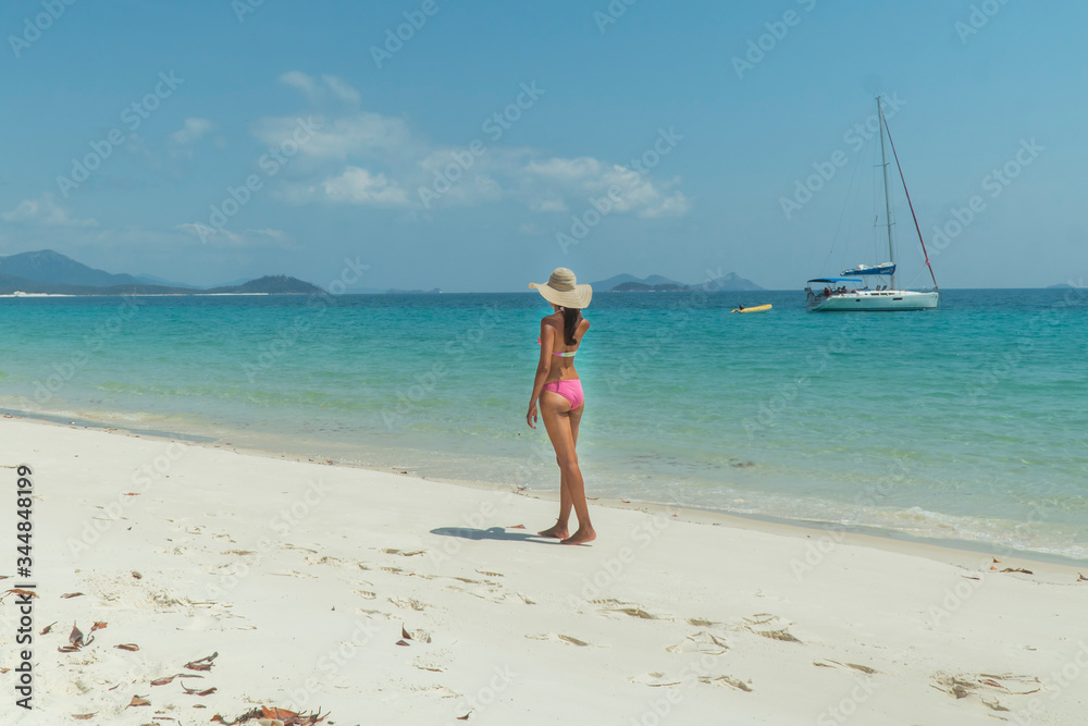 Woman on paradise blue beach. Tourist on Whitsundays beach, white sand, in pink bikini & hat, with aqua turquoise ocean. Travel, holiday, vacation, paradise, exotic. Whitsundays Islands, Australia. Woman on paradise blue beach. Tourist on Whitsundays beach, white sand, in pink bikini & hat, with aqua turquoise ocean. Travel, holiday, vacation, paradise, exotic. Whitsundays Islands, Australia.