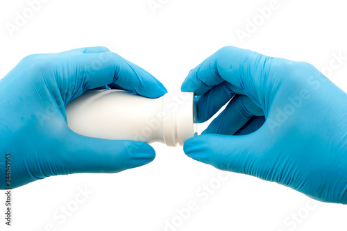 Closeup of two hands with blue surgical gloves opening a bottle of vitamins