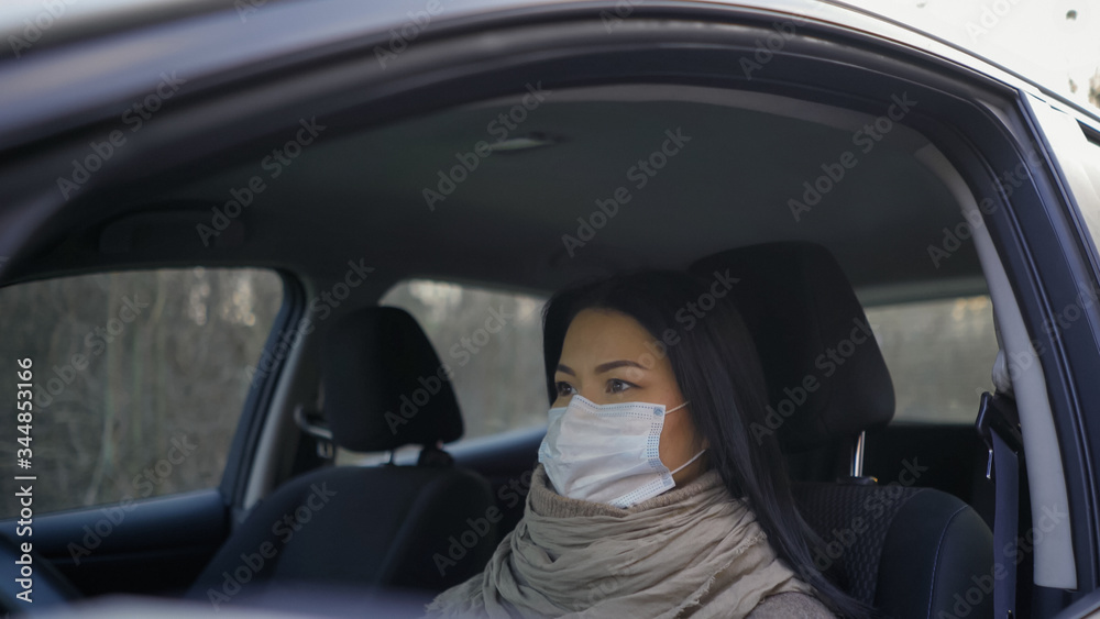 Woman driving car wearing protective mask in the empty quarantined city