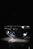Blueberries in a bowl with water on dark background and reflection
