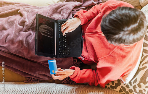 Woman lying on the sofa and shopping online from home with her tablet and credit card