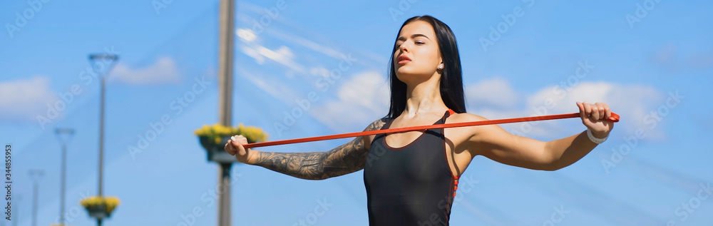 Fit brunette woman, blurry face, holds two old dumbbells during sunny day and looks at you banner Fit brunette woman, blurry face, holds two old dumbbells during sunny day and looks at you banner