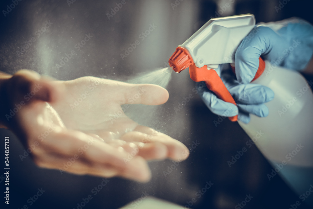A doctor sprays disinfectant on kid's hands