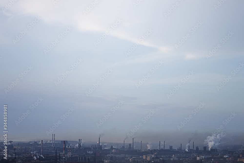 Metallurgical production complex with smoking chimneys against a dark sky. Ecological problems, environmental pollution, ecology.