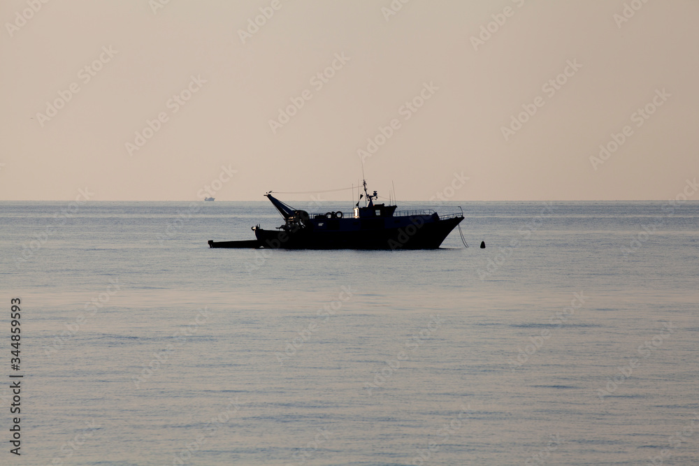 Fishing boat silhouette moored offshore (no people around)