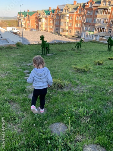 A little girl walks in a city park. Cute baby on a walk in nature.