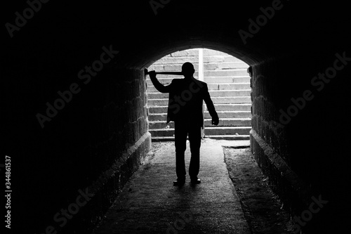 A man with a bat in a dark alley 