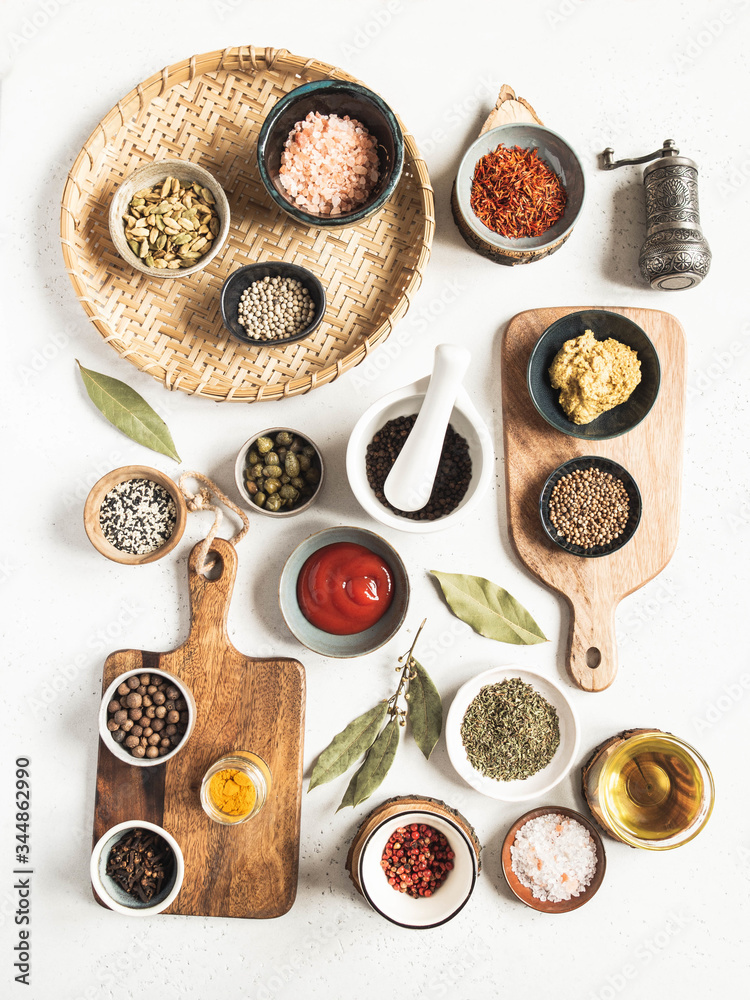 Various dry spices and sauces on a light background. Flat lay of small bowls with dijon mustard, olive oil, ketchup, capers and spices. T Various dry spices and sauces on a light background. Flat lay of small bowls with dijon mustard, olive oil, ketchup, capers and spices. T