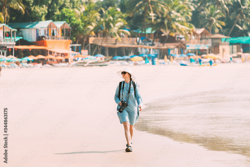 Canacona, Goa, India. Young Caucasian Lady Woman With Camera Walking Along Seashore On Palolem Beach In Summer Sunny Day