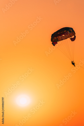 Parasailers Flying On Colorful Parachute In Sunset Sunrise Sky. Active Hobby. Sunshine photo