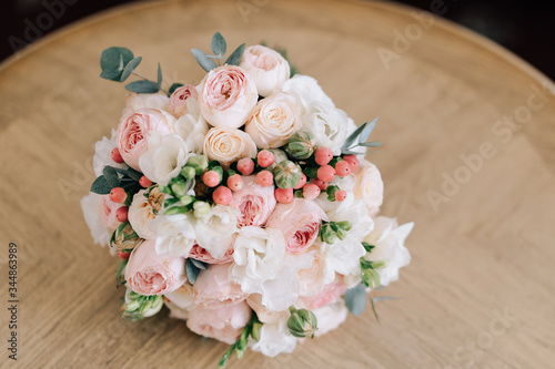 wedding bouquet on beige wood background small white beige roses eucalyptus with red ribbon