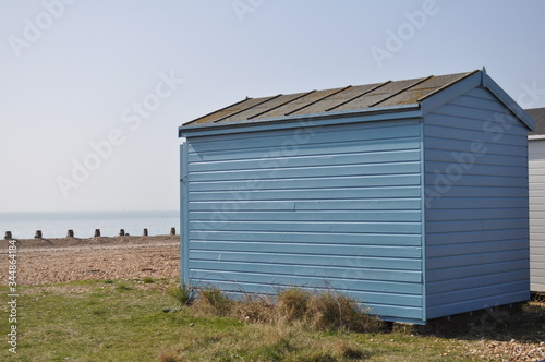 Beach huts lined up in front of the beach with a clear blue sky on a summers day. © AlexMoorePhotography