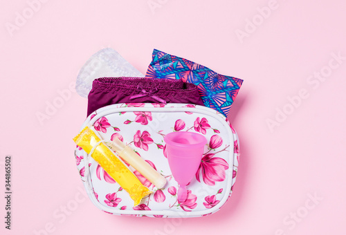 Copa menstrual de silicona. Neceser con artículos de higiene íntima para la menstruación como compresa, tampón y copa menstrual. Salud de la mujer e higiene alternativa. Fondo rosa