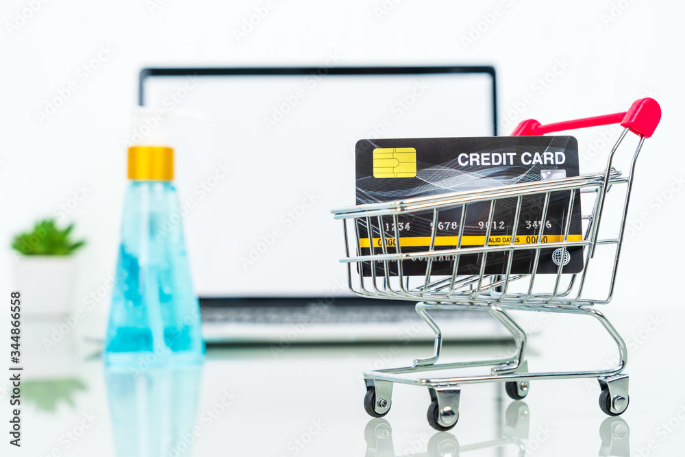 Credit card front of laptop screen with hand sanitizer and surgical mask
