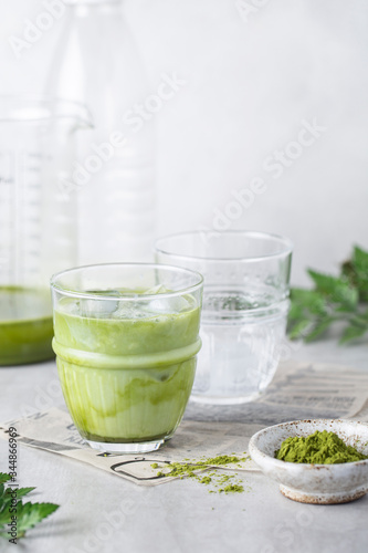 matcha tea with ice and milk in a glass on a grey background