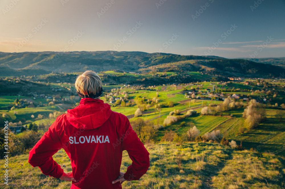 Slovak runner standing on the top of the hill and looking at colorful spring morning landscape