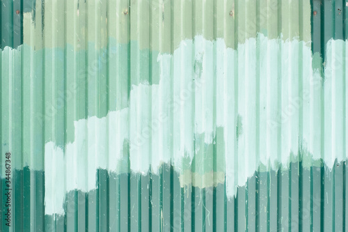 Fragment of aluminum fence  is painted in different shades of green paint . Abstract background.