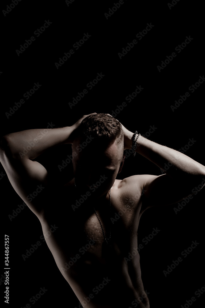 Unknown muscular guy posing on a black background. Unknown muscular guy posing on a black background.