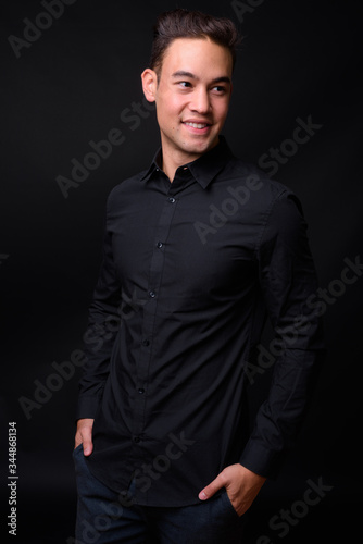 Young handsome multi ethnic businessman against black background © Ranta Images