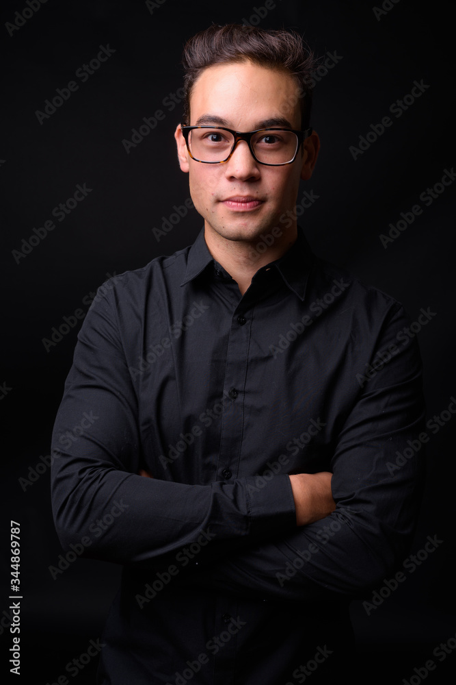 Fototapeta premium Young handsome multi ethnic businessman against black background