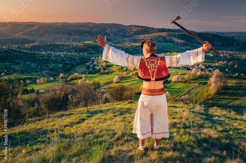 Happy young man with open arms dressed in traditional slovak folk dress standing in beautiful spring landscape in sunrise light photo