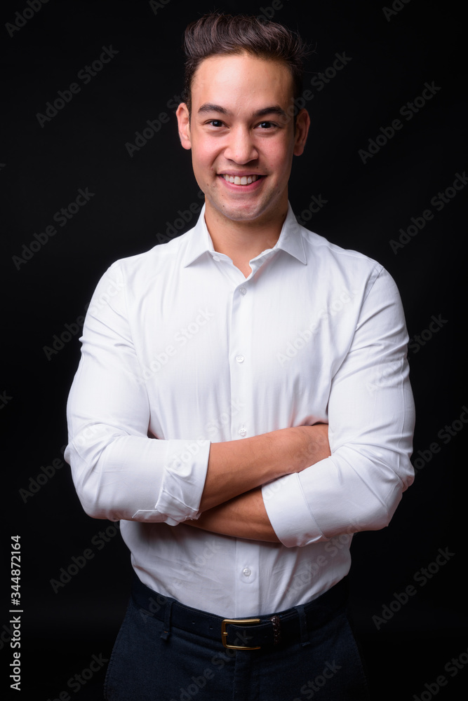 Young handsome multi ethnic businessman against black background Young handsome multi ethnic businessman against black background