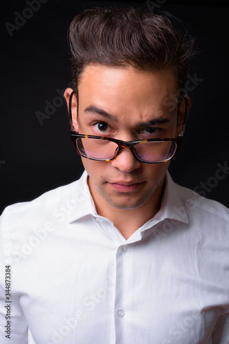 Young handsome multi ethnic businessman against black background