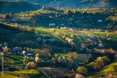 Morning light in spring landscape. Beautiful green rural agricultural fields, small houses, blossom trees, warm sunrise light. Slovakia, Europe