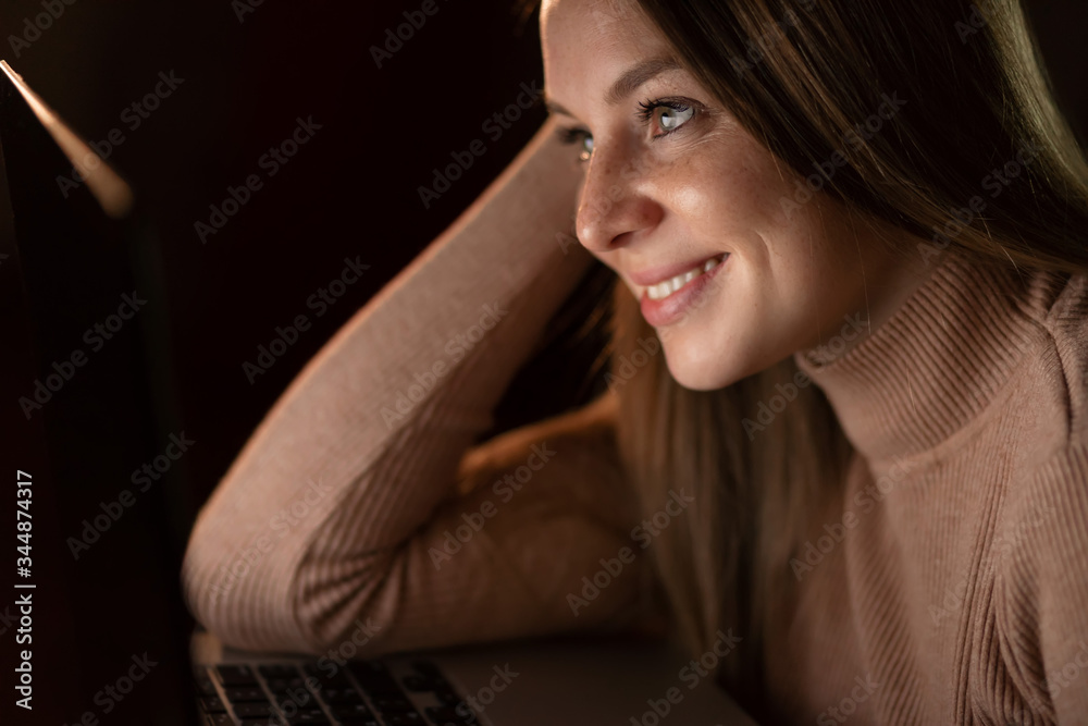Happy woman checking laptop content sitting at home in the night Happy woman checking laptop content sitting at home in the night