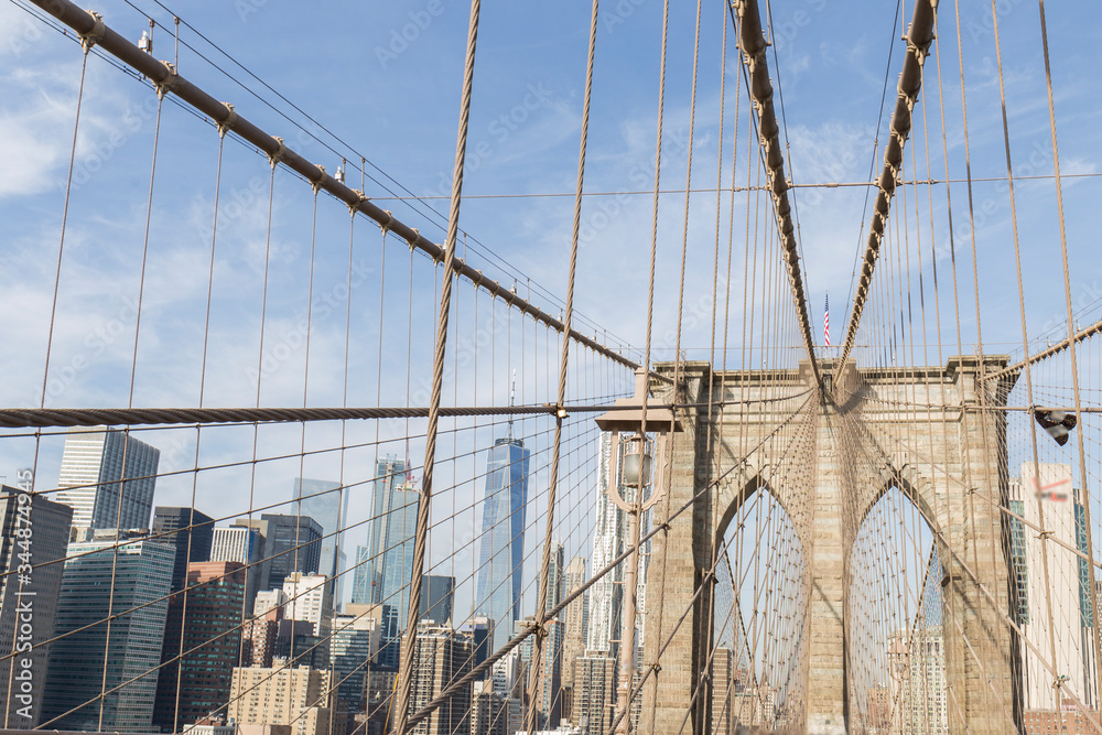 Obraz premium New York City buildings viewed from the Brooklyn Bridge, cables and bridge fencing create geometric shapes