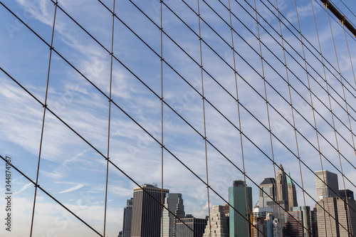 New York City buildings viewed from the Brooklyn Bridge, cables and bridge fencing create geometric shapes © Eloy