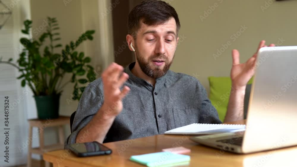 Handsome Eastern European man working from home during Corona virus quarantine lockdown, having online video chat with his colleagues