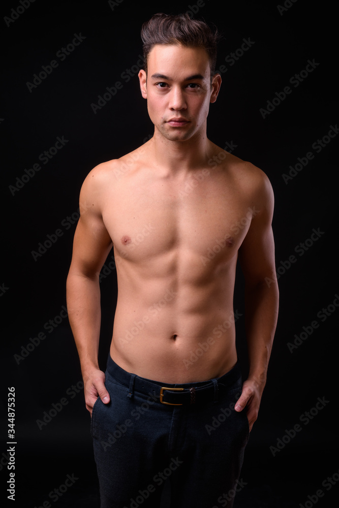 Fototapeta premium Young handsome multi ethnic man shirtless against black background