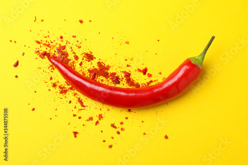 Tasty chilli pepper and powder spice on yellow background